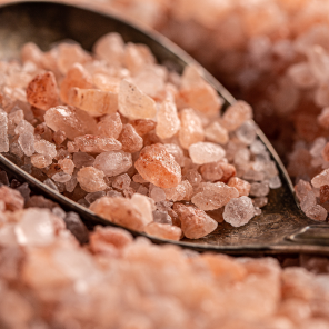 medium coarse of himalayan salt scooped by a deep metal spoon in a paper bag