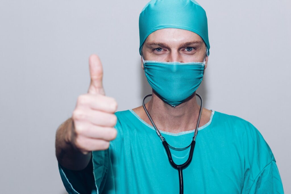 a doctor surgeon wearing his medical outfit in color green while wearing a cap, face mask, stethoscope