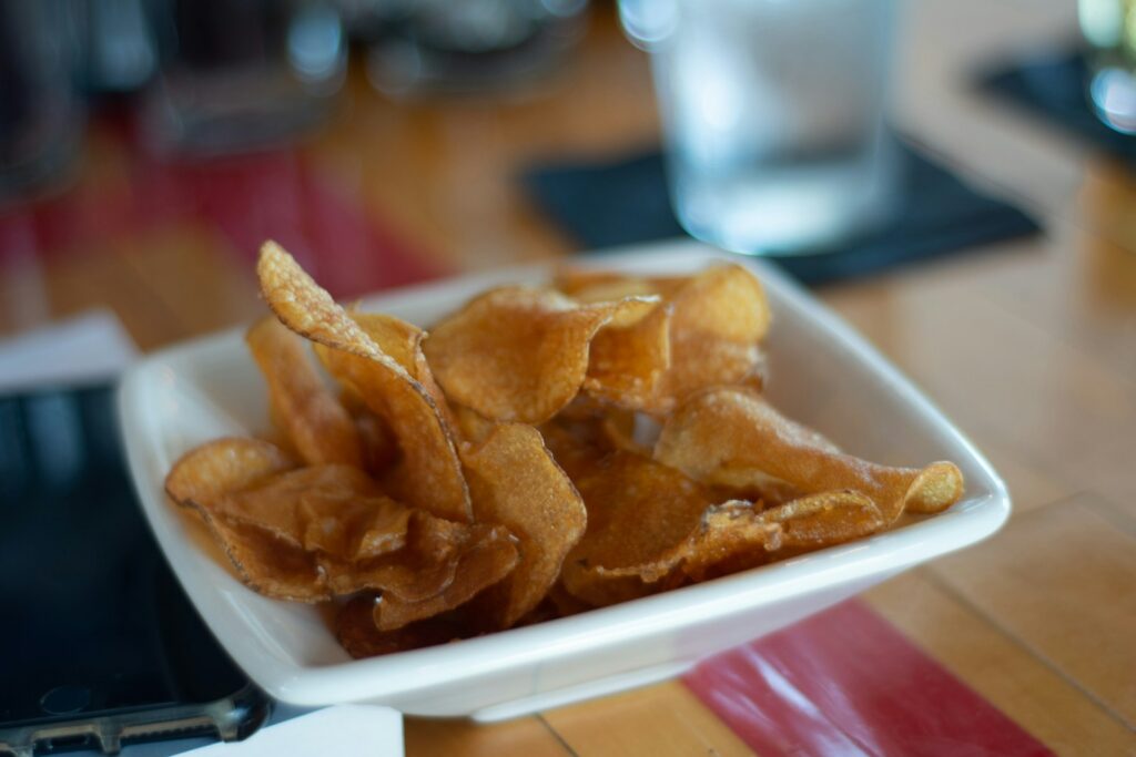 fried potato chips that are thinly cut and placed on a white square plate dish