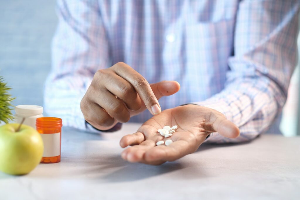 a white old diabetic man holding white medicine pills placed in an orange plastic bottle prescribed by his doctor