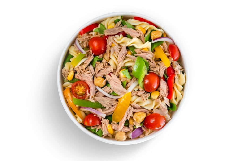 vegetable salad with tomatoes, yellow bell peppers, and tuna in white ceramic bowl