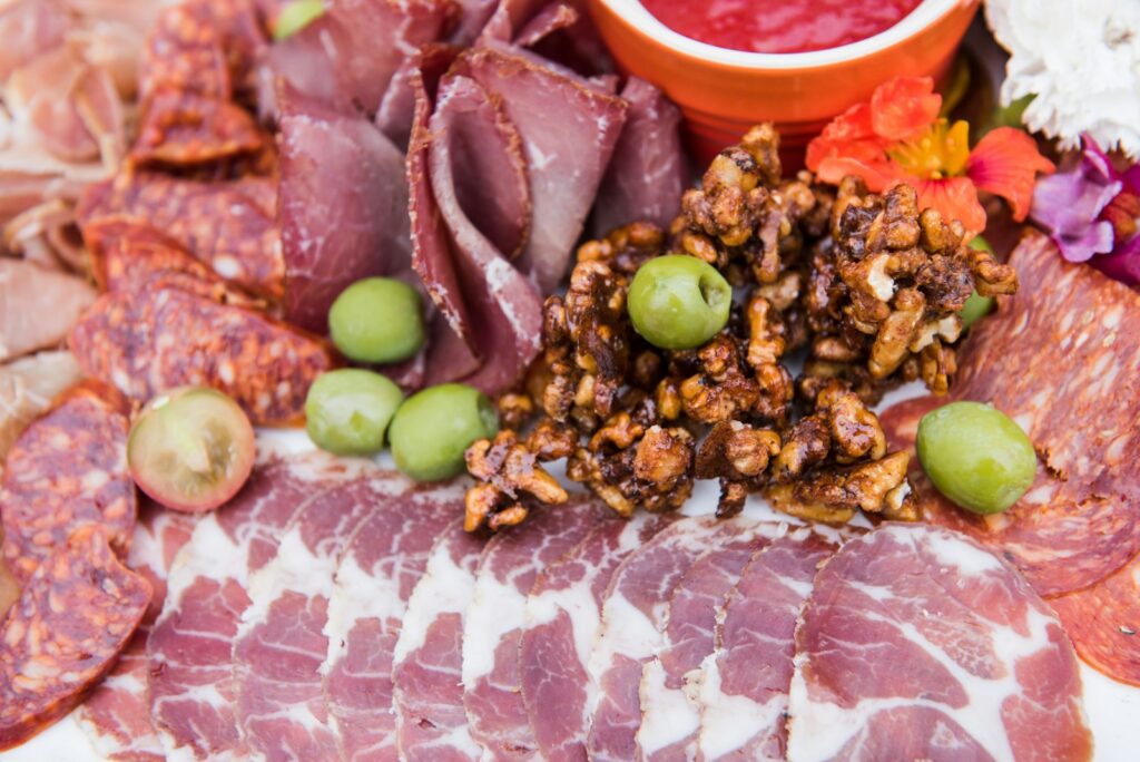 cured meat in a charcuterie tray with prosciutto, salami, pastrami, olives, and other deli meats