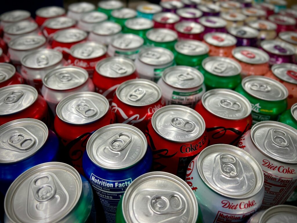 a large group of tin cans of soda with color blue, red, green, and orange cans