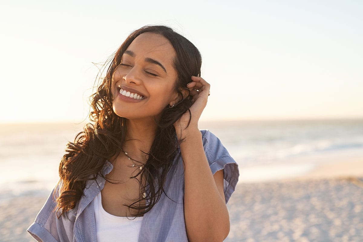 happy woman on the beach after starting a probiotic